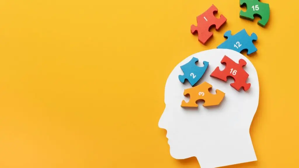 Silhouette of a person’s paper cutout profile filled with colorful puzzle pieces symbolizing the unique brain wiring in autism.